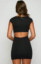 Back view of the black mini dress featuring a wide horizontal cutout detail across the lower back