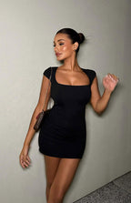 Side view of a black mini dress with a fitted silhouette, short cap sleeves, and side waist cutouts